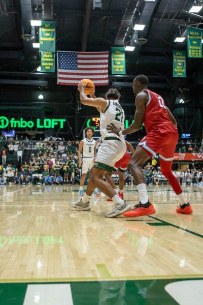 A mens basketball player holds the back of another basketball player holding the ball