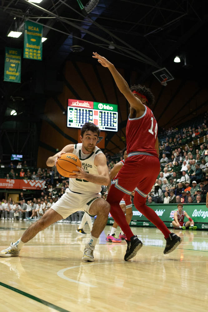 A mens basketball player moves around another basketball player during a sports game.