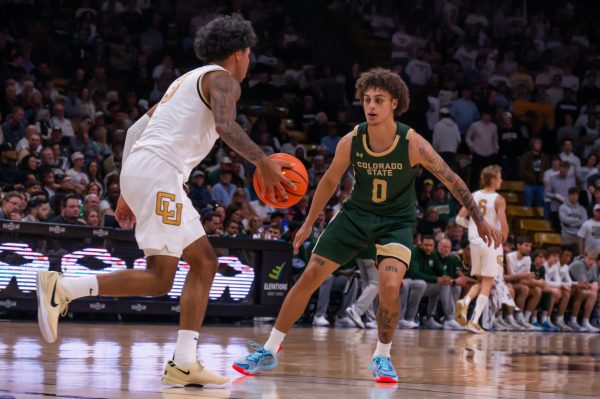 A player in a green and gold uniform in front of a player in a white and gold uniform on the court