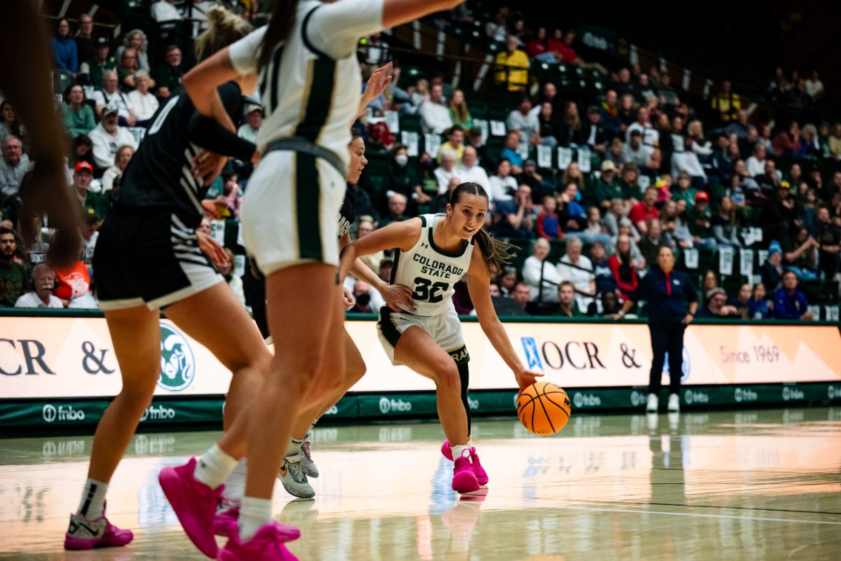 A female basketball player in white and green pushes through a defender in black and white.