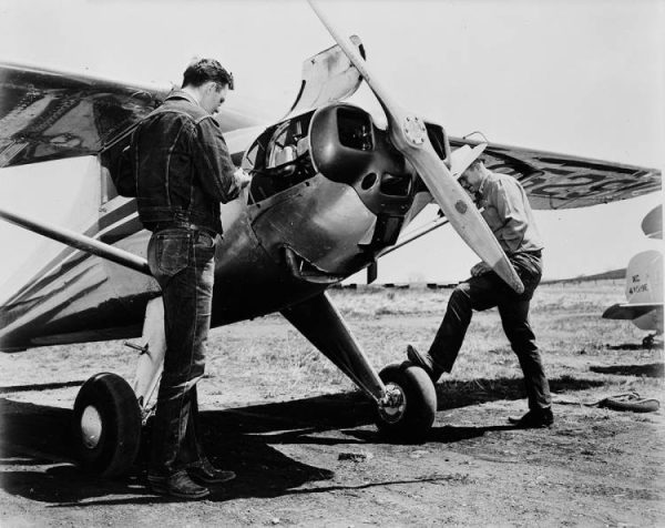 An old photo of two men fixing a small plane