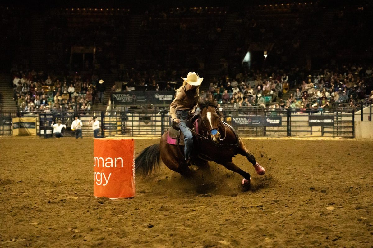 A woman turns her horse around an orange barrier