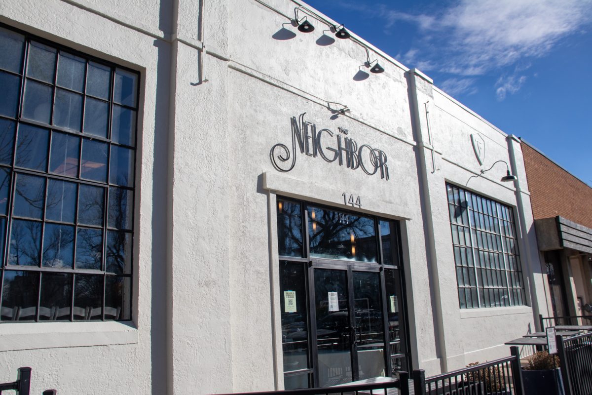 A white building with black text that says, "The Neighbor."