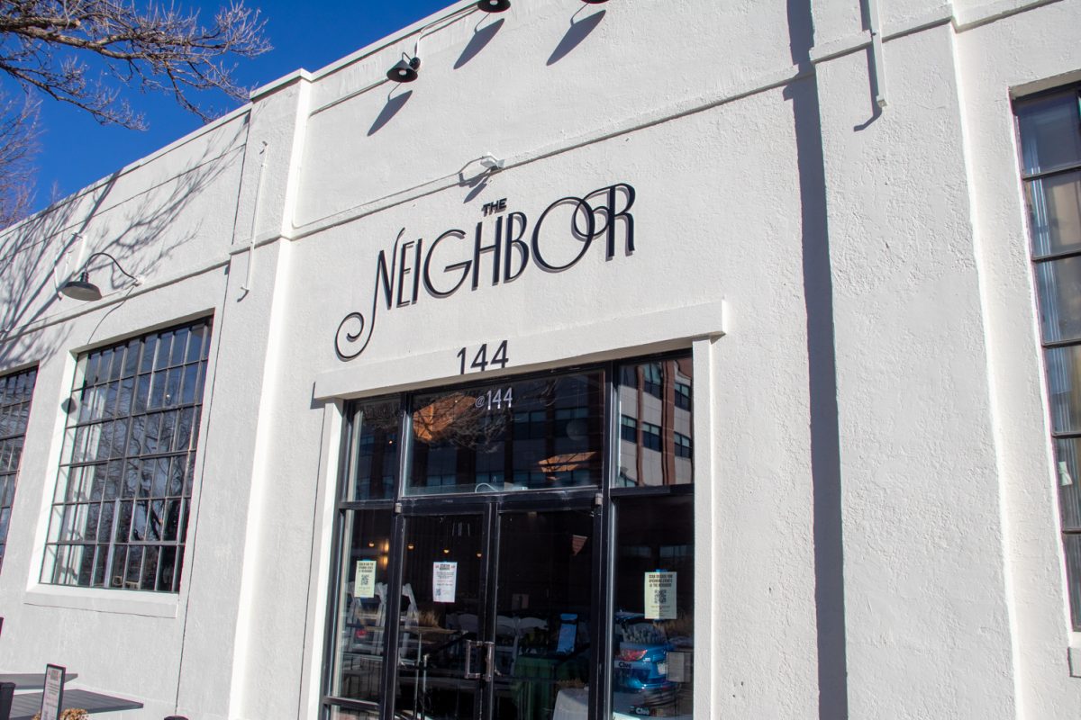 A white building with black text that says, "The Neighbor."
