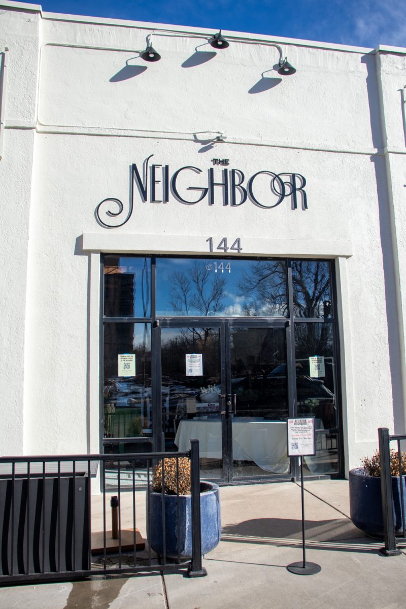 A white building with black text that says, "The Neighbor."