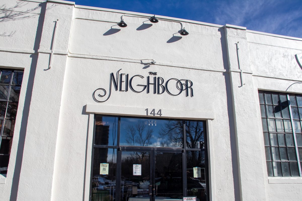A white building with black text that says, "The Neighbor."