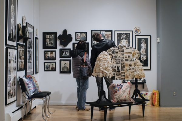 A man and woman gaze closely at a wall full of framed portraits, all embroidered with notes of text, which are part of the “Remember Me” exhibit by Jane Waggoner Deschner at the Museum of Art Fort Collins Feb. 8.