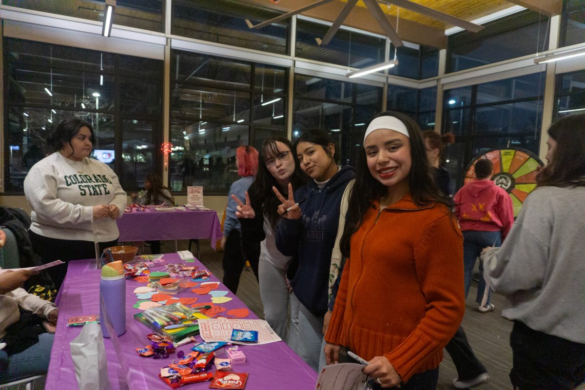 Three people stand in front of a table.