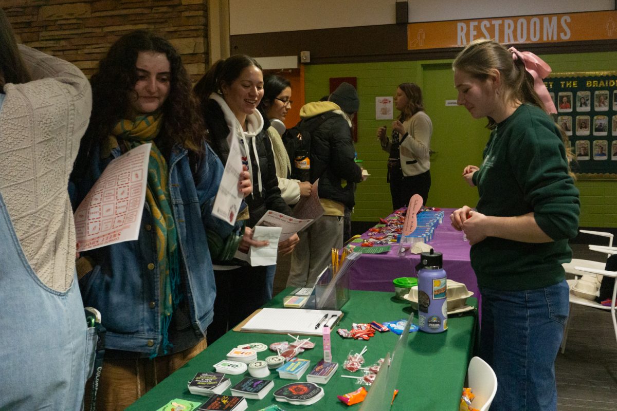 A person behind a table talks to others in front of the table.