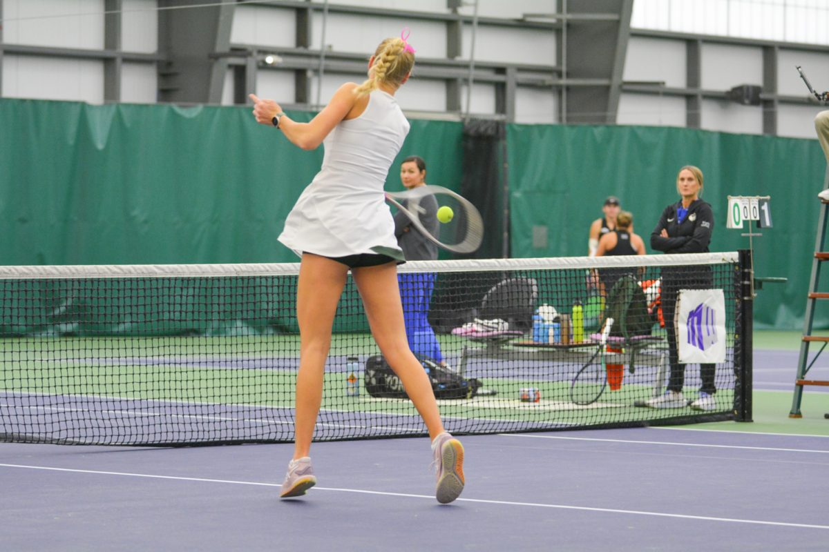 A girl in a tennis outfit hits the tennis ball.