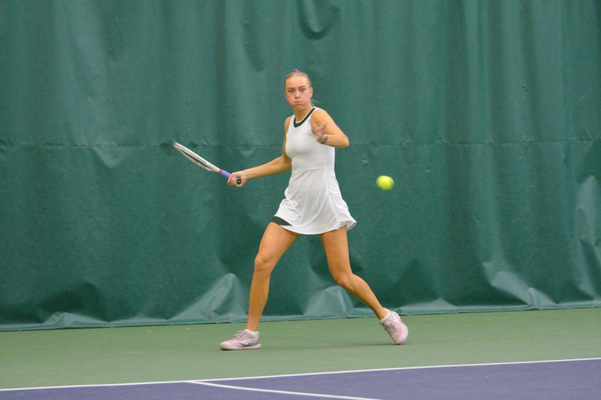 Girl in white tennis outfit getting ready to hit the tennis ball.