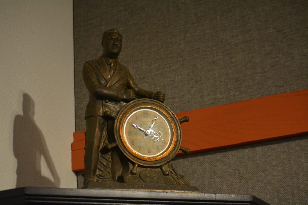 A statue of a man holding a clock like a steering wheel