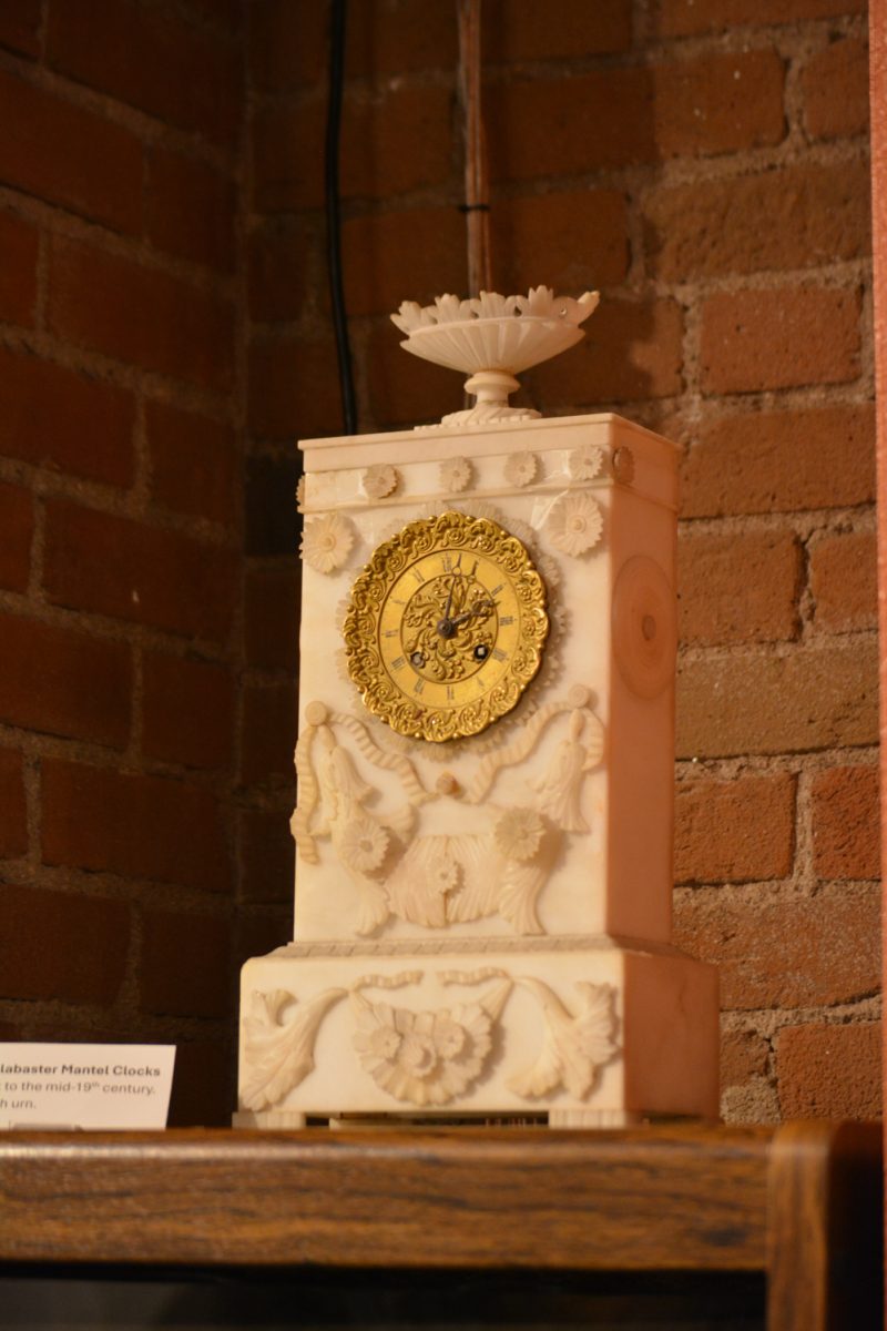 A white and gold clock with designs on it