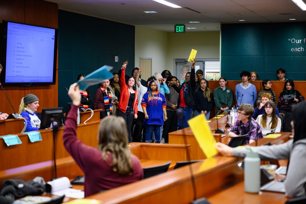 Senators of the Associated Students of Colorado State University raise their hands and placards to approve a motion to continue allowing students to speak on their experiences during a senate meeting Feb. 19.