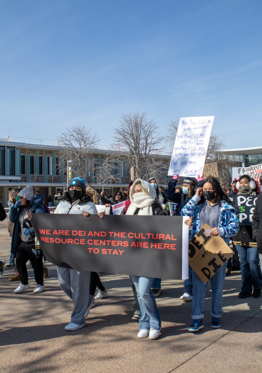 A large group of students walk together all lead by a large banner in front of the group.