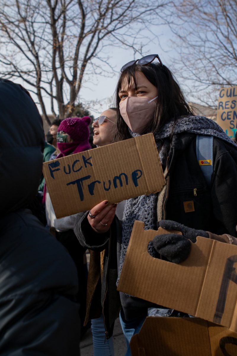 A woman holding a "Fuck Trump" sign.
