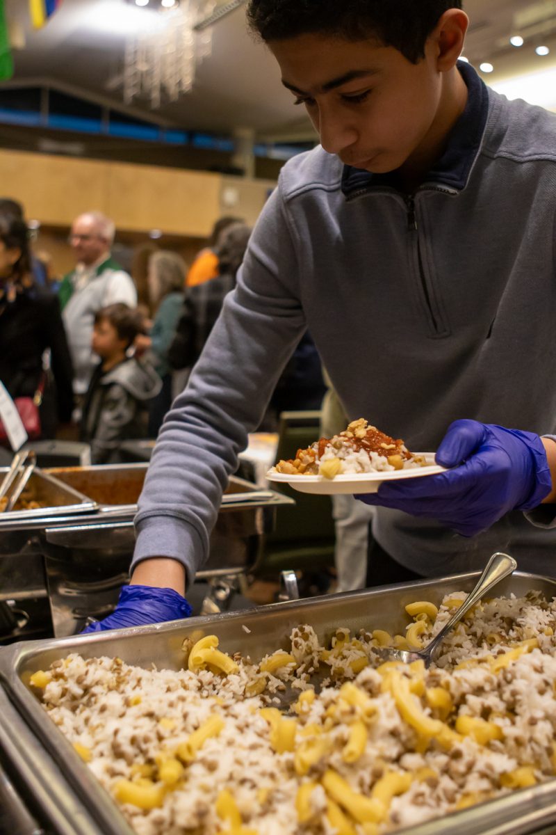Hazem Gad serves Koshari with the Muslim Student Association during the World Unity Fair Feb. 22. "It's an Egyptian dish," a booth member said. "It's composed of rice, lentils, chickpeas, fried onions and tomato sauce with a garlic sauce on top." The MSA was advertising their Ramadan Iftar event during the fair.