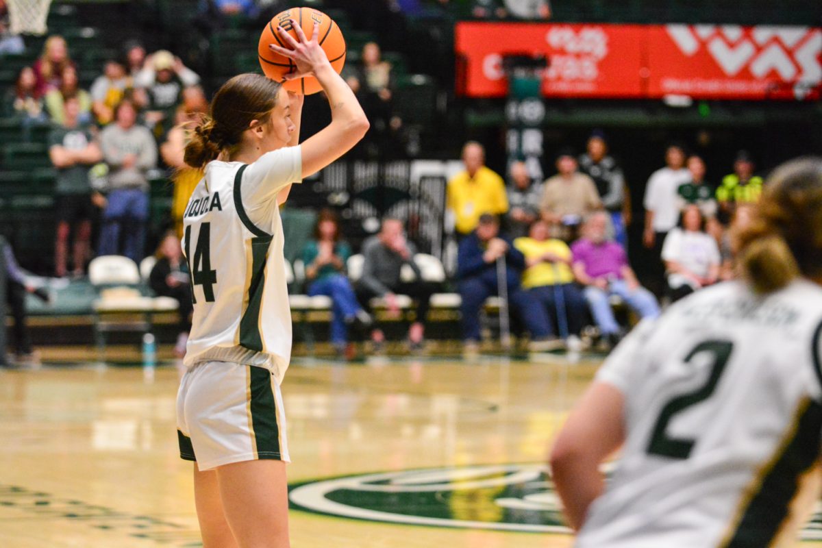 player in green and white jersey holding a ball above her head