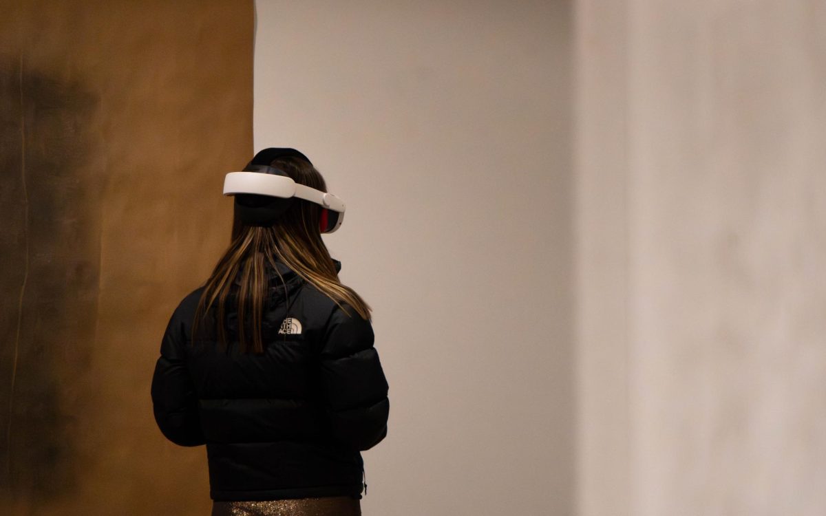 A woman stands facing away from the camera with a VR headset on her head