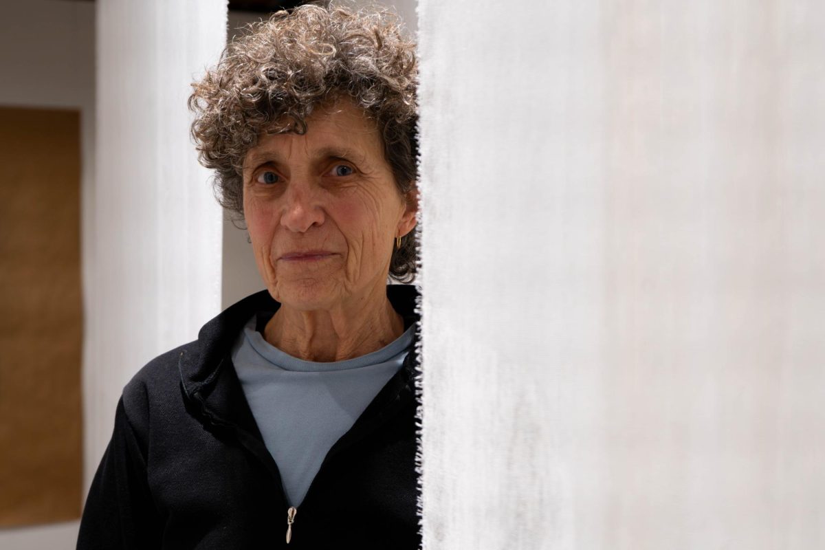 A woman stands next to a white linen sheet hanging from the ceiling