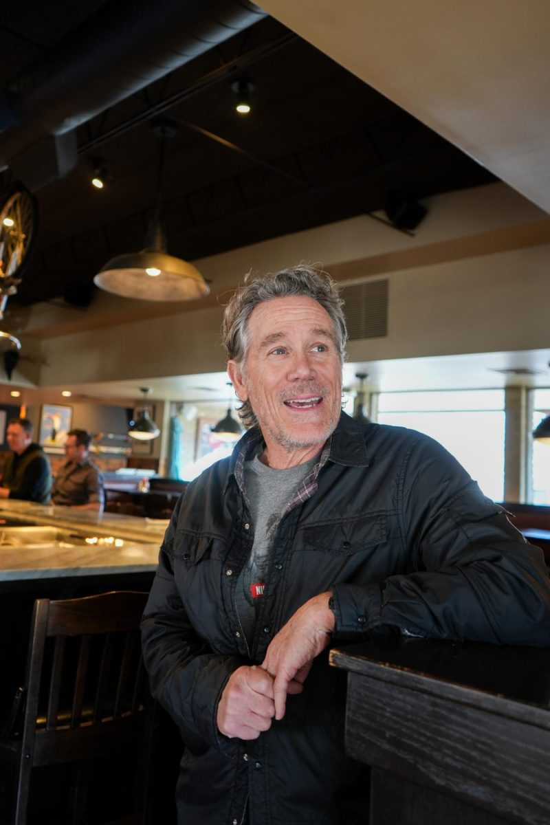 A man in a restaurant laughs, looking off camera.