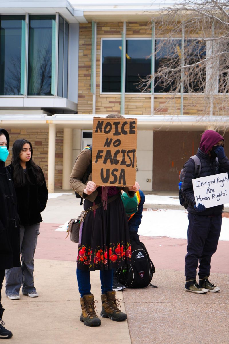A protestor in front of the Lory Student Center holds a sign that reads, "No ICE, No Fascist USA."