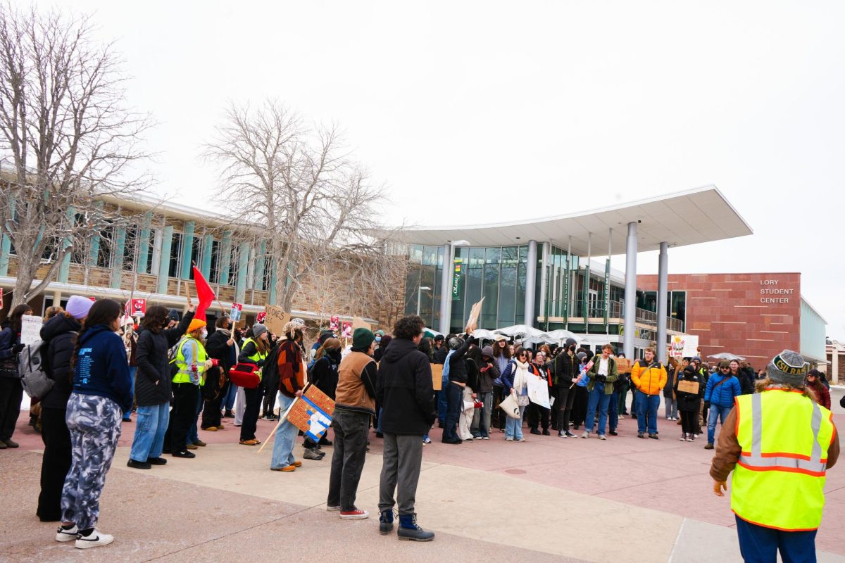 Students gather to protest with signs in front of the Lory Student Center.