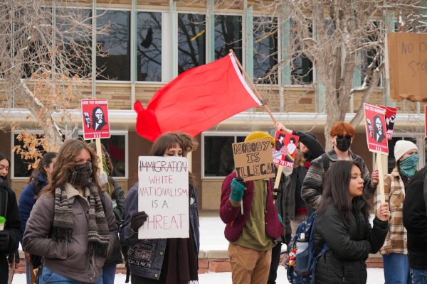 Students gather in protest in front of the Lory Student Center. They hold signs that read, "Immigration (crossed out) white nationalism is a threat," "Nobody is illegal," and "Love thy neighbor."