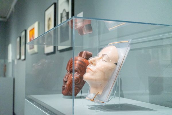 Sleeping Mask by Gillian Wearing, a hyperrealistic woman’s face, and Tattoo Mask by John Collins, a deep red and intricately detailed mask, sit on display in a glass case together at "The Body Construct: Between Flesh and Thought," an exhibition at the Gregory Allicar Museum of Art in the University Center for the Arts Feb. 27.