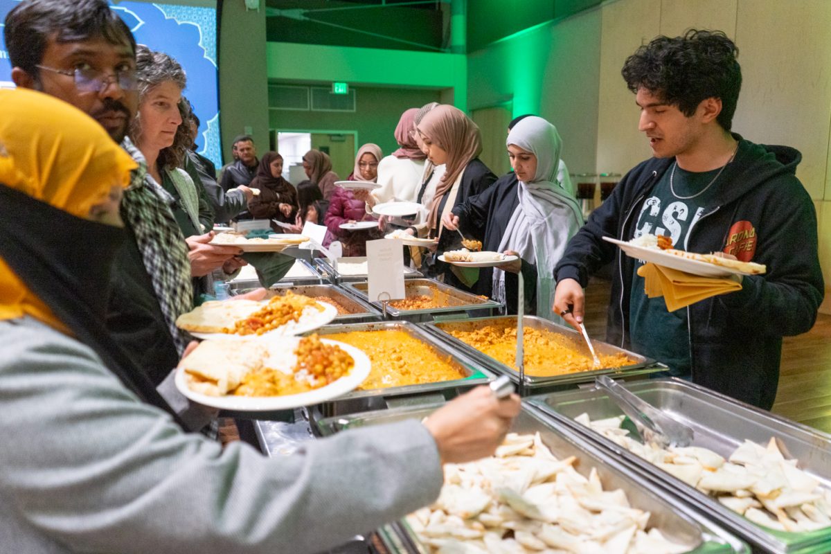 Guests fill their plates at a buffet-style serving table with white rice, chana masala, butter chicken and more in the Lory Student Center’s Grand Ballroom, decorated with green lights and balloons for the Ramadan Iftar Dinner Celebration at Colorado State University March 3.