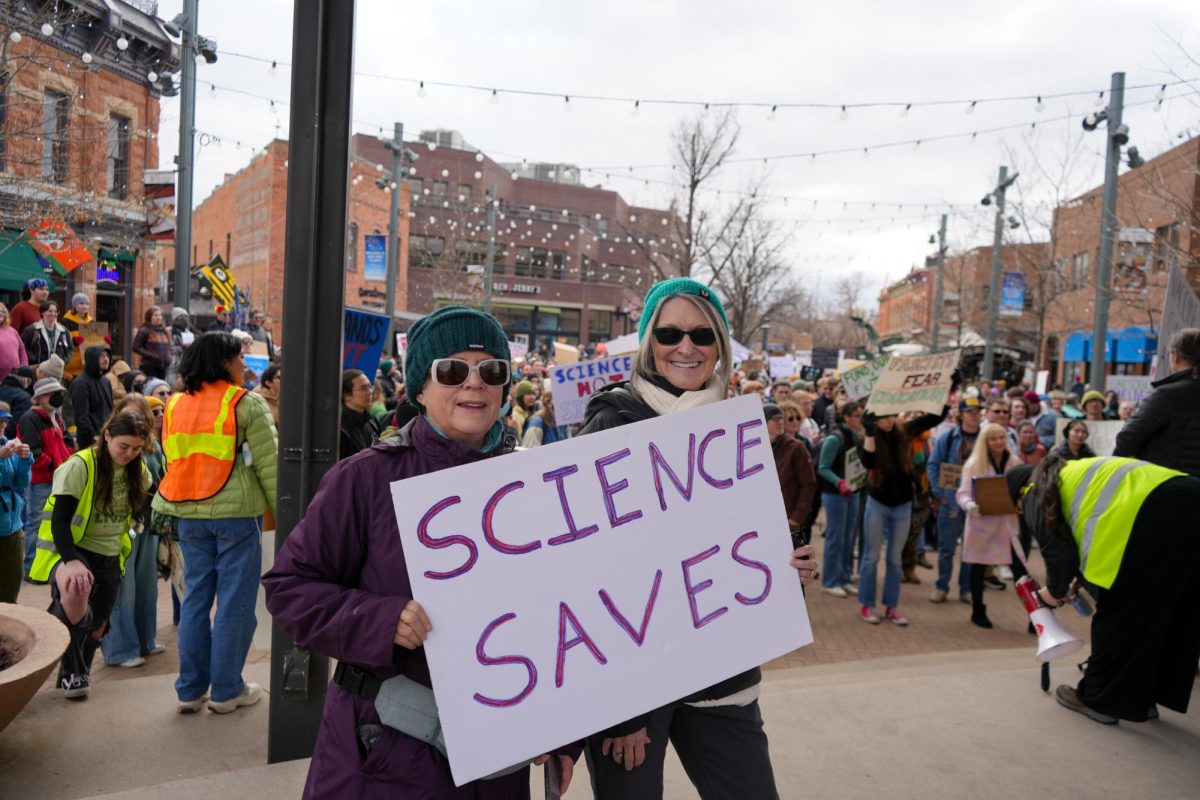 Demonstrators May Monahan and Sherri Kase pose for a photo with their sign in Old Town Square in support of the nationwide protest "Stand up for Science" on March 7 2025. 