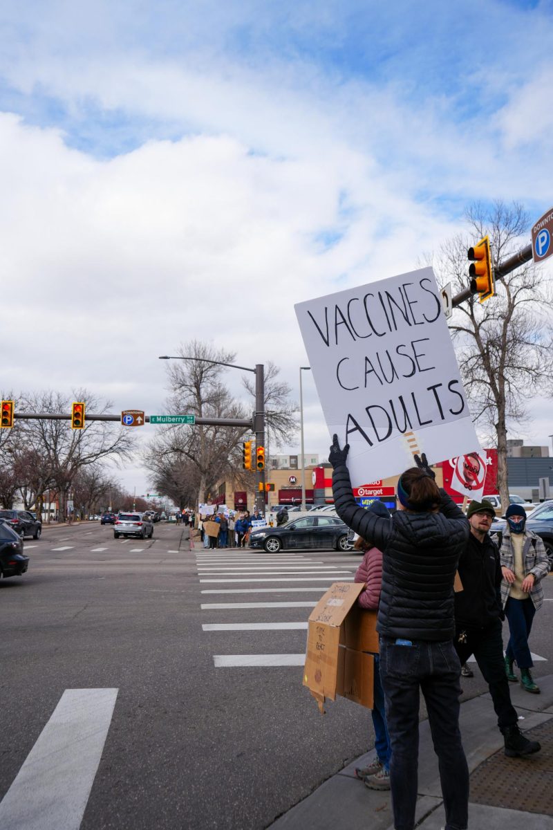 A protester holds up a sign on the intersection of College Ave. and Mulberry St. on the way back from Old Town Square. Many signs like this one protested the new wave of anti-vaccine rhetoric that has gained traction in recent years. 