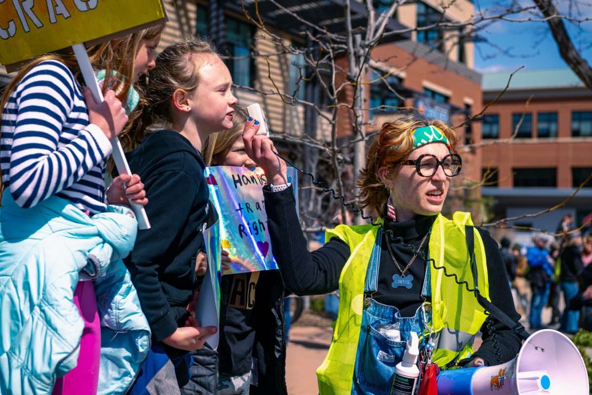 Protester Ella Smith holds up a microphone for a kid to speak through during the "Hands Off" protest in Fort Collins April 5.