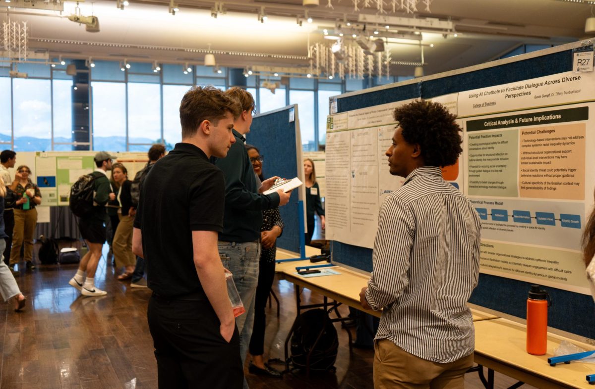 Gavin Gumpf, student presenter at the CURC Showcase, discusses his research with an attendee on April 17. 