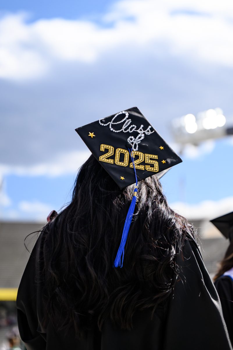 A Colorado State University graduate looks up at the big screen of Canvas Stadium as they walk onto the field May 16.