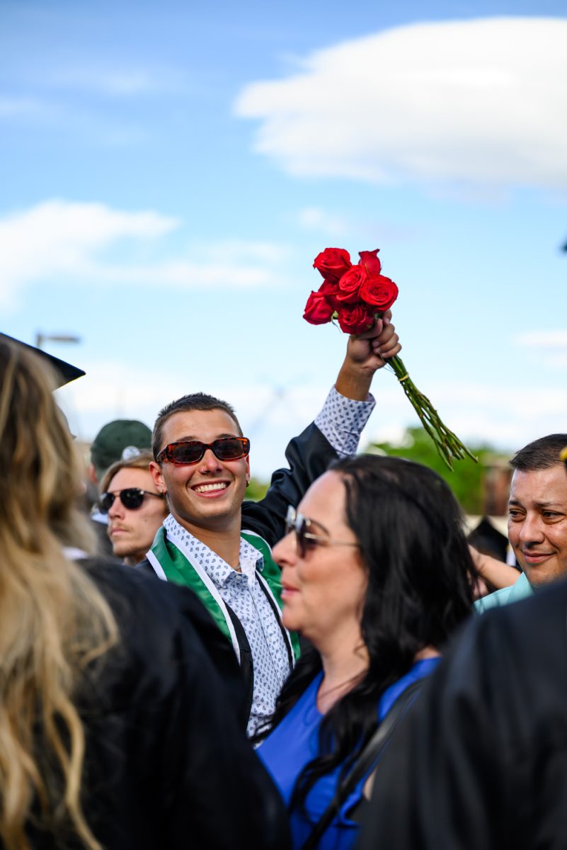 A Colorado State University graduate smiles at the camera while holding up a small bouquet of roses after the university-wide commencement ceremony May 16.