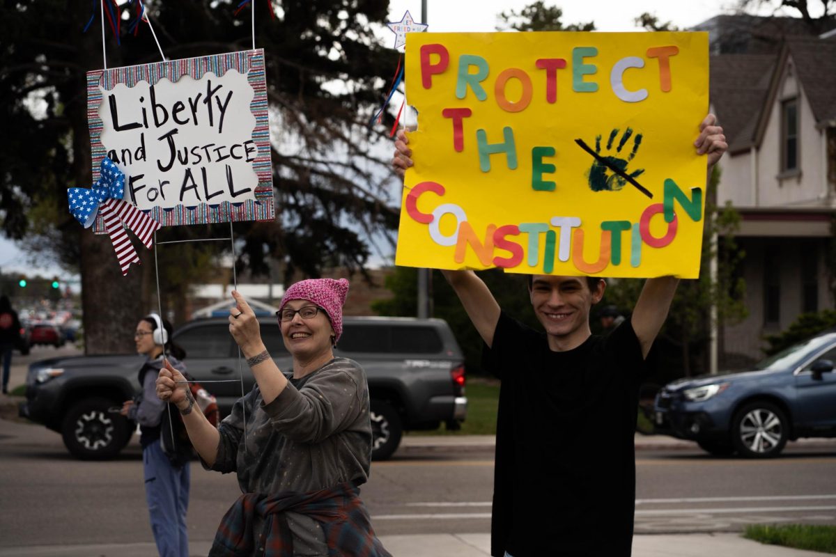 Protestors Dylan Ryan and Shawnee Brecka hold signs on the corner of College Ave. and Lake Street May 1. Part of the May Day protests, a nation-wide movement protesting recent federal actions, Fort Collins residents lined College Ave.  
