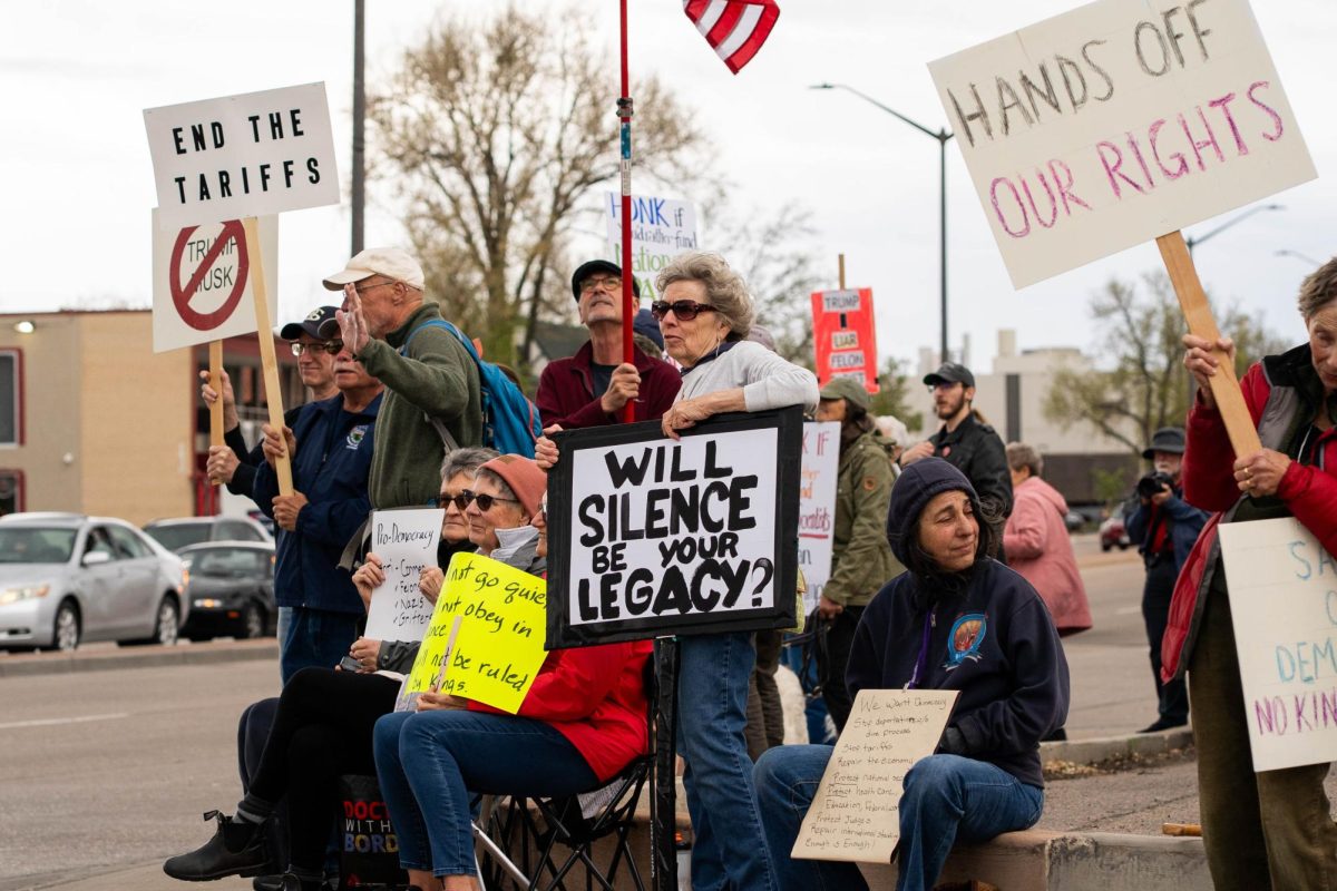 A group of protestors holds signs up to passing cars on the corner of College Ave. and Prospect road May 1.  Part of the May Day protests, a nation-wide movement protesting recent federal actions, Fort Collins residents lined College Ave.  