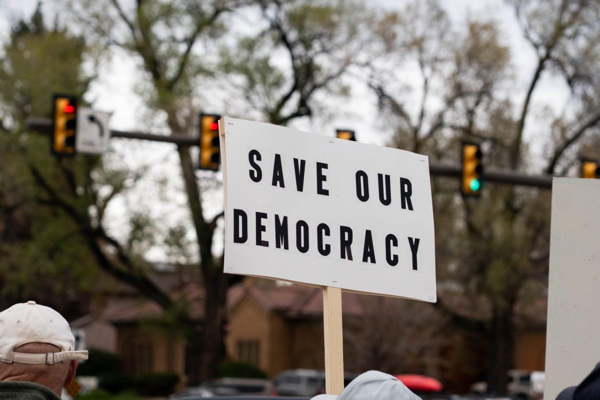 A protestor holds a sign reading "Save Our Democracy" on College Ave. May 1. Part of the May Day protests, a nation-wide movement protesting recent federal actions, Fort Collins residents lined College Ave.  