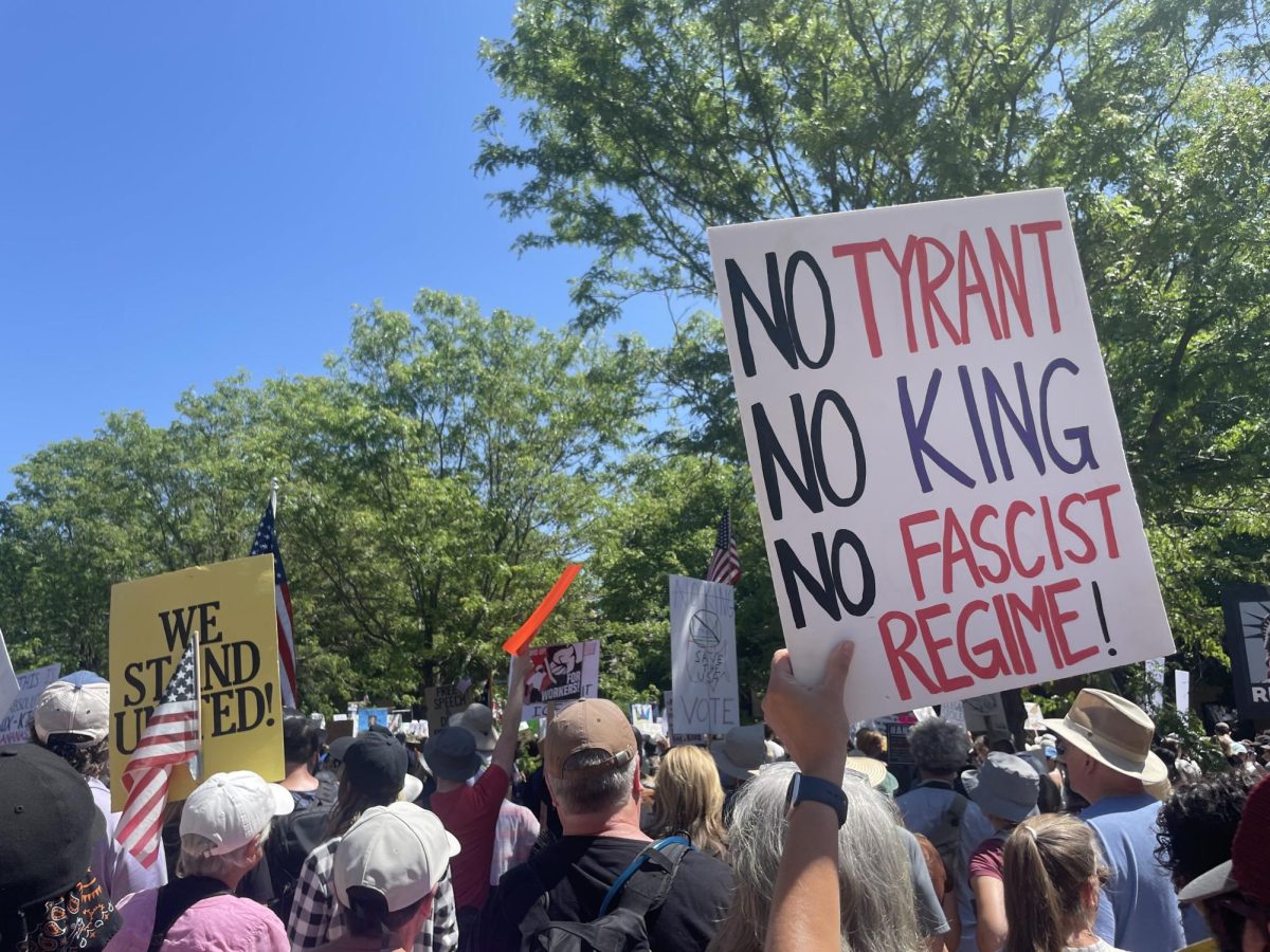 A sign that reads "No Tyrant, No King, No Fascist Regime" is held above thousands of demonstrators preparing to march from the Lory Student Center Plaza to College Avenue as part of the nationwide "No Kings" protest June 14.