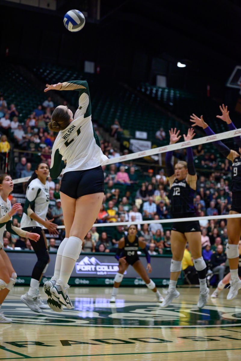 Middle blocker Eve Wilson (27) jumps to spike the ball over the net during Colorado State University's game against the University of Washington Aug. 30. CSU lost 2-3.