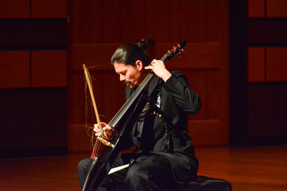 A man closing his eyes before he performs while he holds his cello.