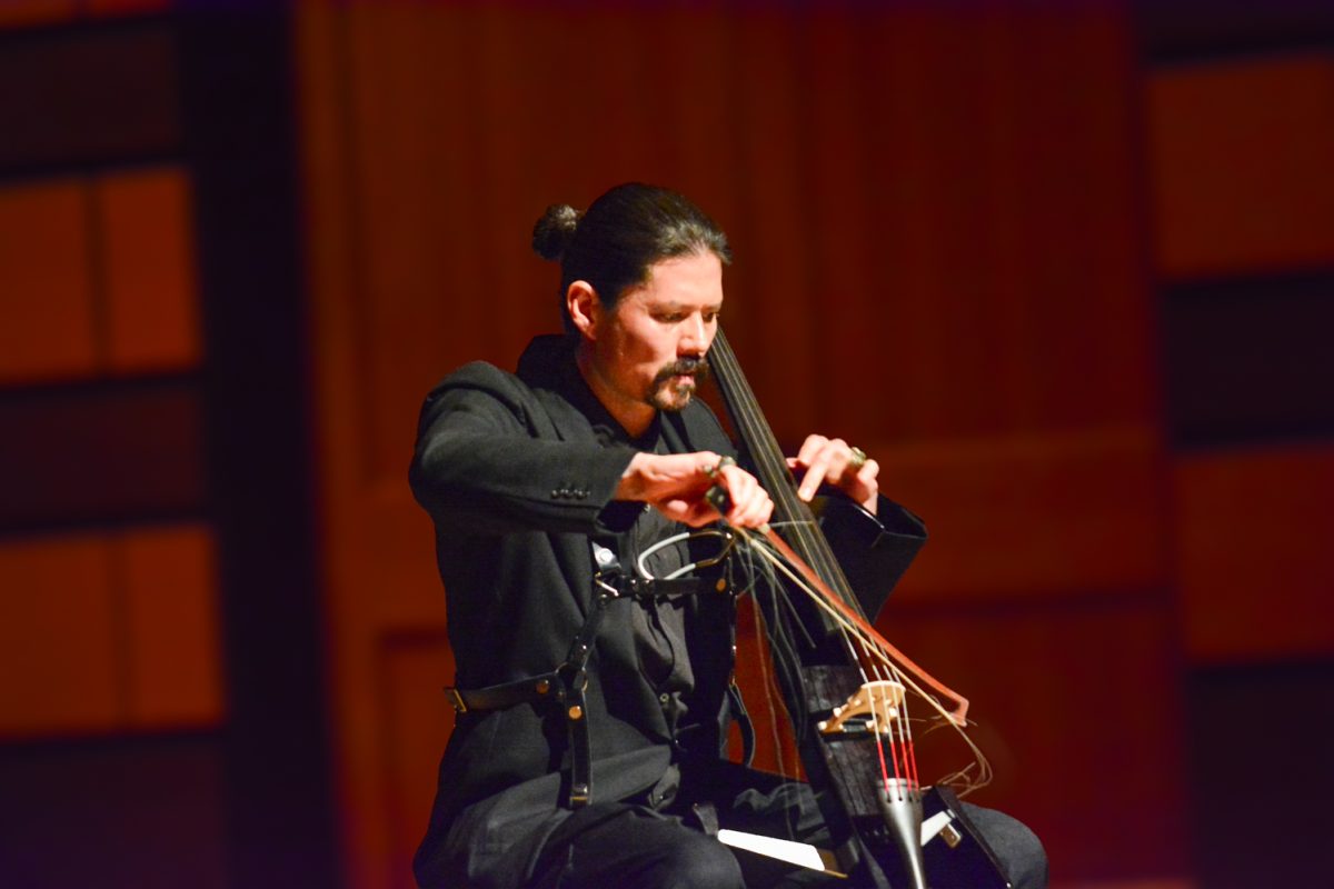 A man playing his cello on stage.