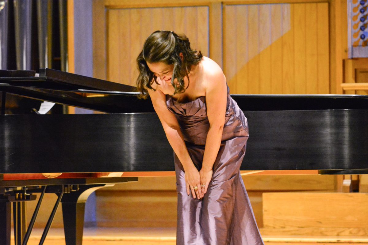 A woman in a purple dress bowing to the crowd.