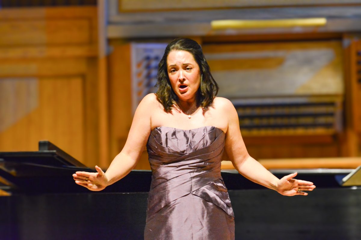 A woman in a purple dress singing to the crowd.