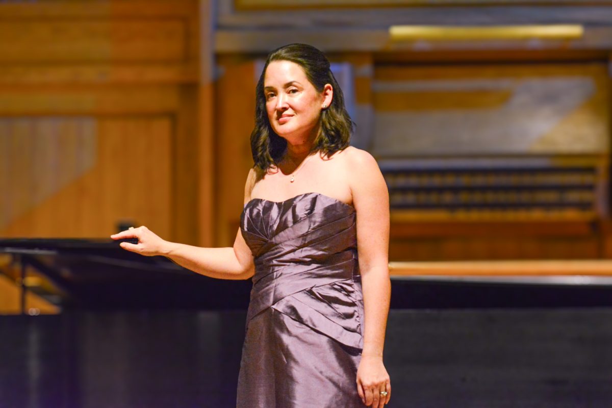 A woman in a purple dress looking out to the crowd after finishing her performance.