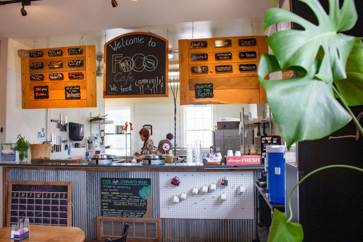 The serving counter at FoCo Cafe has chalk-written menus hanging from the ceiling, a mug wall, a sign with “community needs,” a calendar and a full kitchen behind it, with staff cleaning up for the day Aug. 29. FoCo Cafe allows customers who don’t have a means to pay for their food with money to complete chores and tasks in return for a meal.