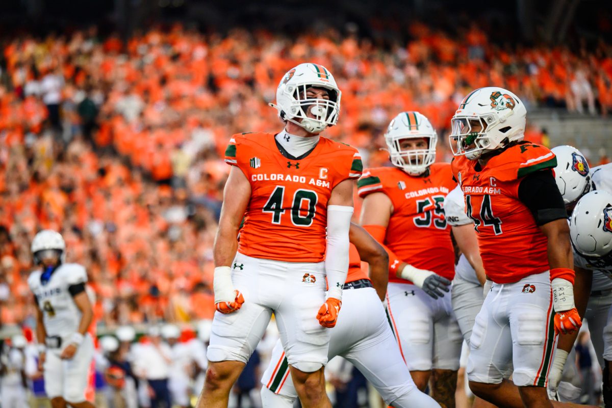 Two football players in orange jerseys cheer each other on.