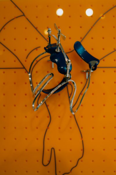 A metal and plastic art piece in the shape of a hand overlayed on top of the outline of one hand grabbing the wrist of another.