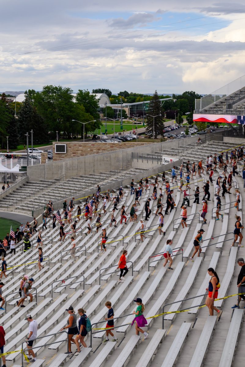 A crowd of people walk up and down rows of stairs in a large football stadium.